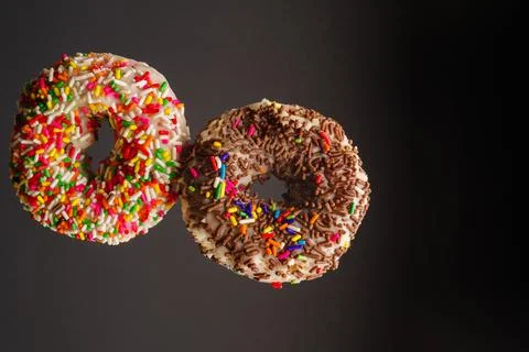 Two multi-colored sweet donuts on a gray background in a frozen flight. Sweet Foto stock