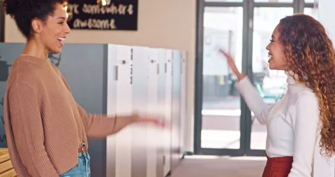 Two multi-ethnic colleagues high five and celebrate success, laughing in office Stock Footage 244535158