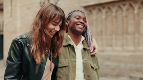 Two multi-ethnic friends walking around and hugging Stock Footage 310453503