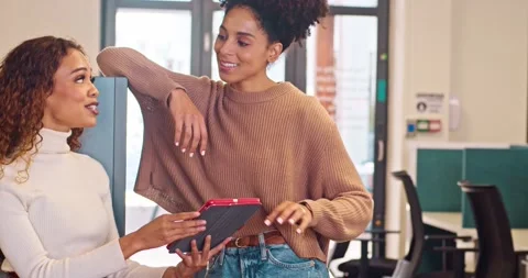 Two multi-ethnic women stand and have informal chat in open plan office, talking Stock Footage 244537997