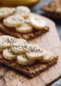 Two multi grain breads with peanut paste, banana slices and chia seeds on a s Stock Photos