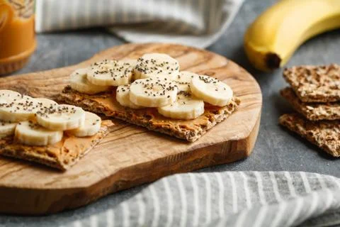 Two multi grain breads with peanut paste, banana slices and chia seeds on a s Stock Photos