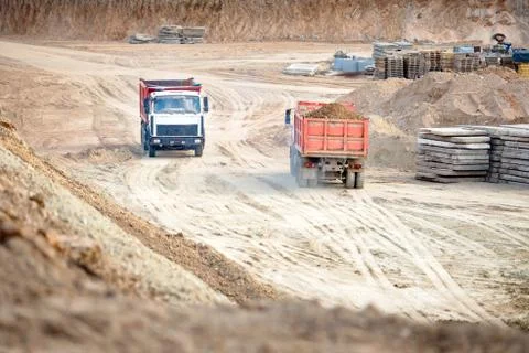Two multi-ton heavy mining dump trucks empty and loaded during removal of Stock Photos