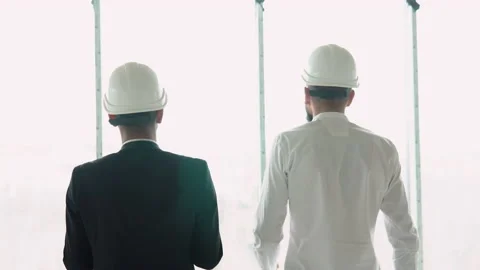 Two multiethnic builders engineers workers in helmets walking on construction at Stock Footage 236477028