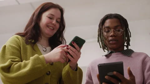 Two Multiethnic Colleagues Discussing Work with Tablet and Smartphone Stock Footage 327768337