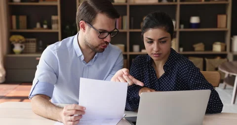 Two multiethnic colleagues sit at desk use laptop discuss paperwork Stock Footage 168962343