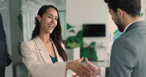 Two multiethnic colleagues talking, shaking hands in office Video stock 283208141