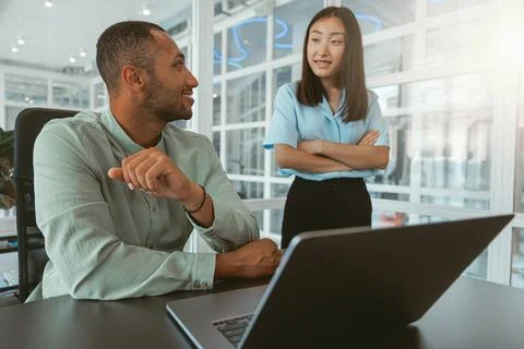 Two multiethnic colleagues talking while working together in modern office Stock Photos