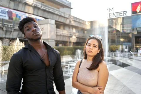 Two multiethnic friends posing seriously in a shopping mall Stock Photos