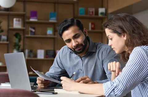 Two multiethnic professionals working together with laptop in office. Stock Photos