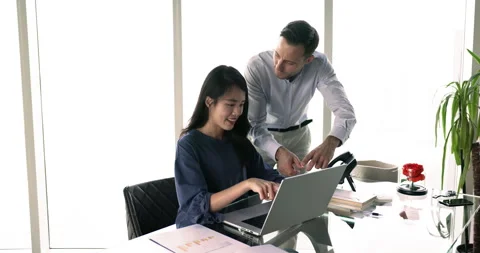 Two multiethnic teammates using laptop at meeting in modern office Stock Footage 281368373