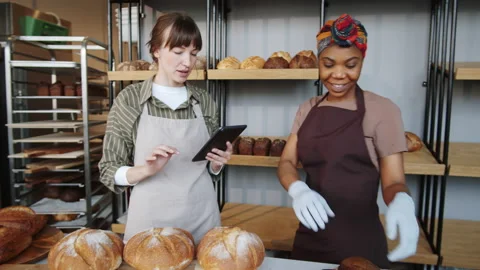 Two Multiethnic Women Using Tablet and Working in Bakery Stock Footage 154444542