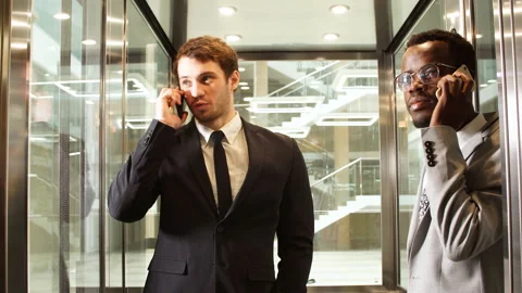 Two multinational Business man standing in elevator and use smartphone. Business Stock Footage 86761430