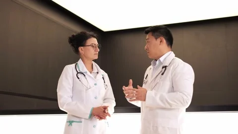 Two multinational doctors standing at reception talking exchanging information. Stock Footage 199806661