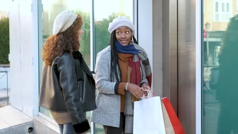 Two multiracial female friends calling and waiting for lift after shopping. Stock Footage 247170762