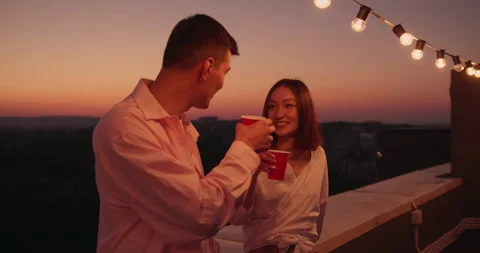 Two multiracial friends chatting together socializing at rooftop party at night Video stock 157534133