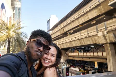 Two multiracial friends embracing while taking a selfie outdoors Stock Photos