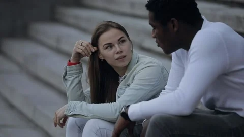 Two multiracial friends talking sitting in a city Stock Footage 132153508