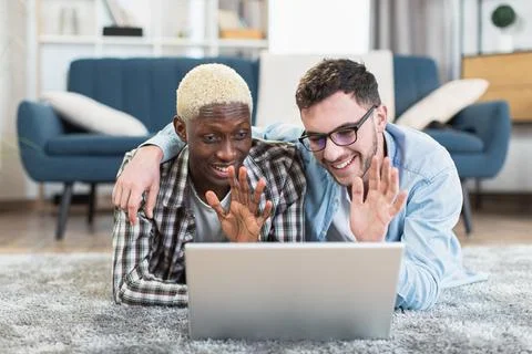 Two multiracial gays using laptop while resting at home Stock Photos