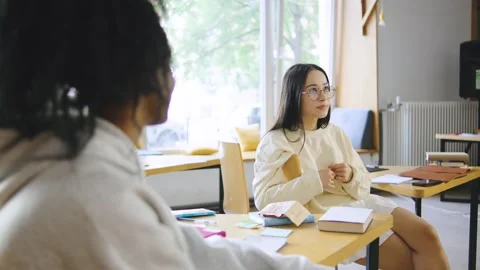 Two multiracial students engaged in a lively discussion while studying at a Stock Footage 300736110