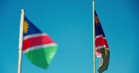 Two Namibian Flags Flying Side by Side in Wind Under Blue Sky Stock Footage 321772081