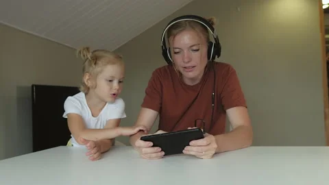 Two naughty daughters distract their mother from work and demand her attention Stock Footage 143481289