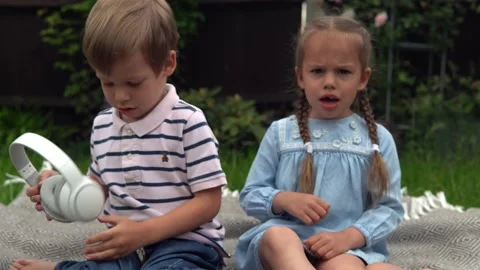 Two naughty Siblings dont share. boy ans girl listening to music on headphones Stock Footage 197463941