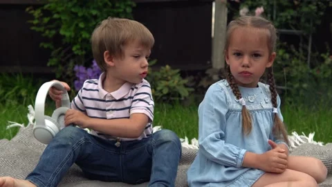 Two naughty Siblings dont share. boy ans girl listening to music on headphones Stock Footage 199666340