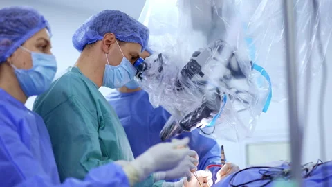 Two neurosurgeons look at microscope performing operation on brain. Stock Footage 293160193