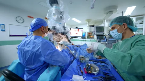 Two neurosurgeons working under surgical microscope with instrument table Stock Footage 335759083