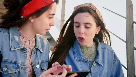 Two nice young Hispanic sisters exploring new app on smart phone device, stays Stock Footage 106194117