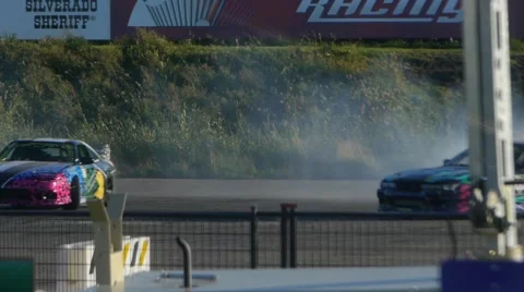 Two Nissan's drift around corner at drift event in summer. Stock Footage 59747454