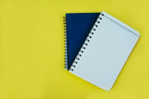 Two note books placed on top of each other over a yellow paper background Stock Photos