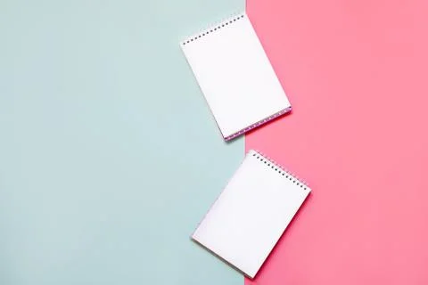 Two notebooks spiral down the middle of a pink and blue background. Stock Photos
