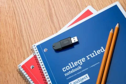 Two notebooks with a usb drive and pencils on a school desk. Stock Photos