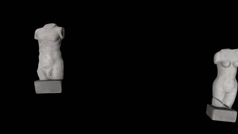 Two nude antique statues - a man's and a woman's - move against a black Stock Footage 155529634