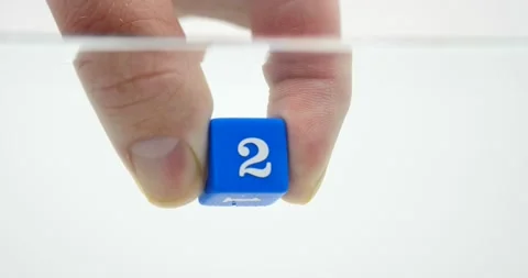 Two number on dice blue held by fingers in water isolated on white Video stock 219520742