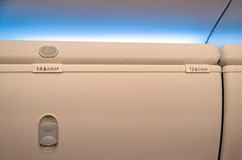 Two numbered overhead compartments are visible in the cabin of an airplane du Stock Photos