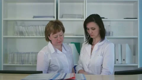 Two nurses sorting out folders and files at hospital reception desk Stock Footage 152861549