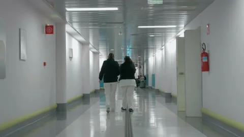 Two nurses walking down a hospital corridor and patients waiting Stock Footage 171628588