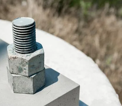 Two nuts threaded on bolt attached to cement block. Foto stock