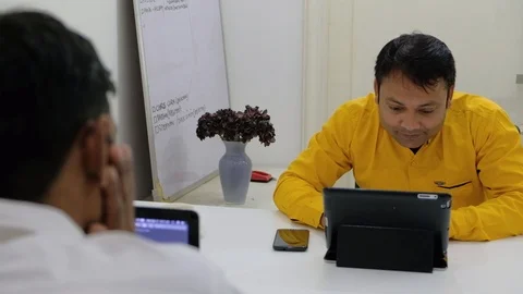Two office colleagues work on their electronic devices and chat in their white  Stock Footage 100025921