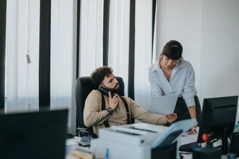 Two office workers collaborating on a document during a busy workday. Stock Photos