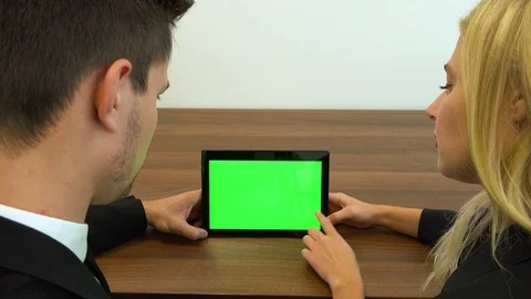 Two office workers, man and woman, sit at a desk and slide at a tablet  스톡 동영상 103459465