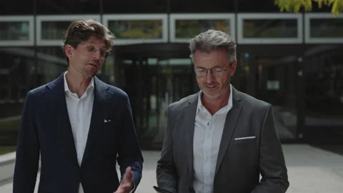 Two office workers in suits walking and talking outdoors Stock Footage 167240204