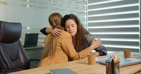 Two office workers talking about failure in recent project hugging to support Stock Photos