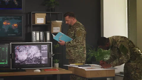 Two officers developing military strategy using maps and intelligence reports Stock Footage 335539403