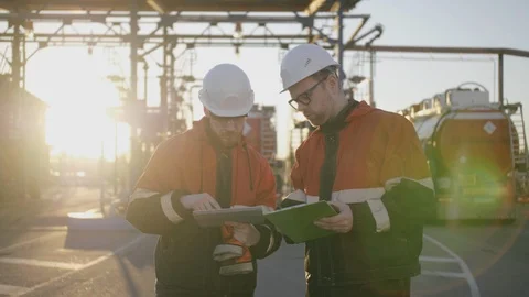 Two oil refinery engineers discuss work. Both look attentively at tablet screen Stock Footage 109528575
