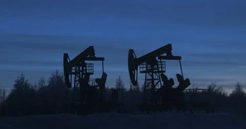 Two oil rigs work against the sunset in winter Video stock 102446340