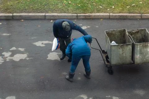 Two old janitors with old empty garbage cart on the street Stock-Fotos